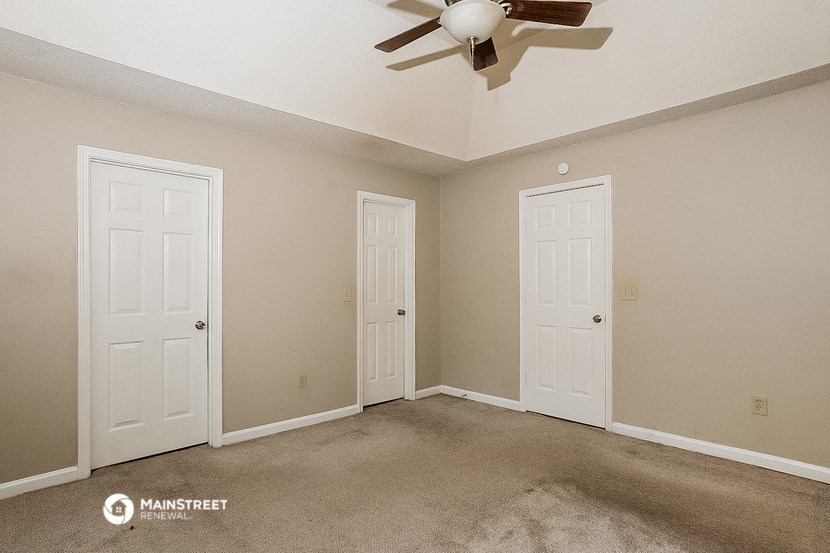 a empty room with two doors and a ceiling fan