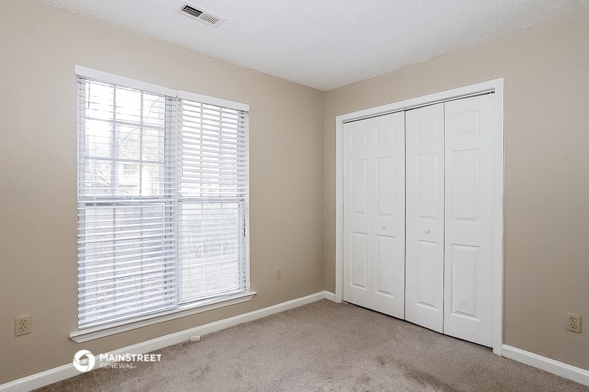 an empty bedroom with two doors and a window