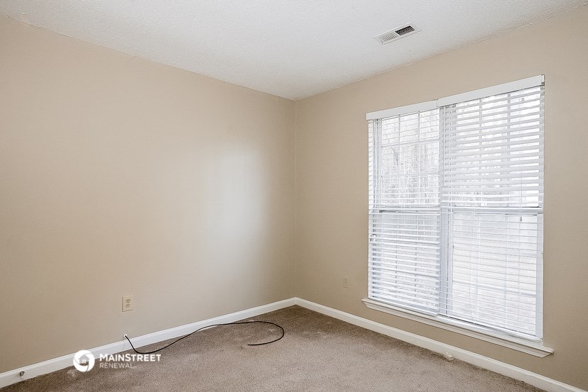 an empty room with a large window and a carpet