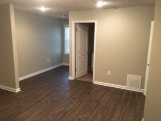 an empty living room with a wooden floor and a door