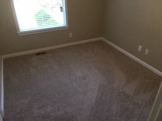 an empty room with a window and a carpeted floor