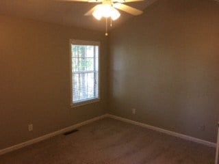 an empty bedroom with a ceiling fan and a window