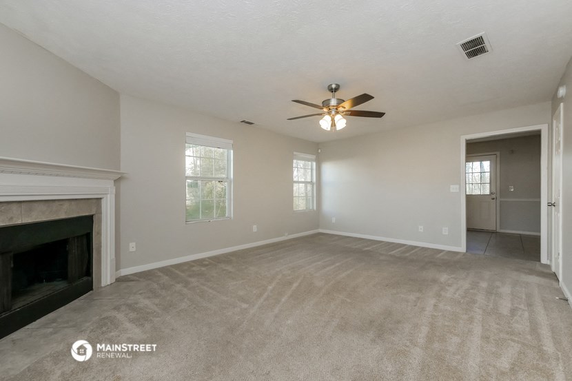 the spacious living room with fireplace and ceiling fan