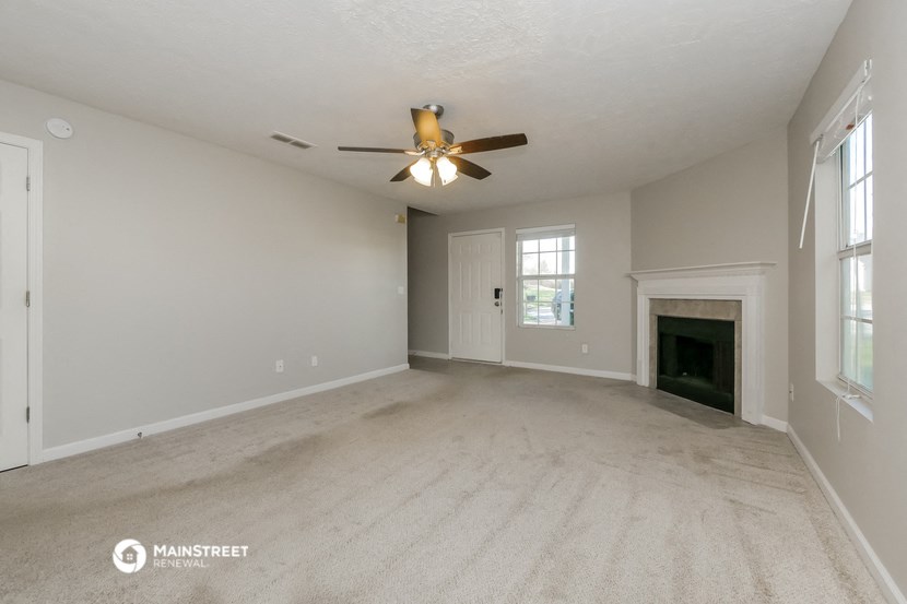 the spacious living room with fireplace and ceiling fan