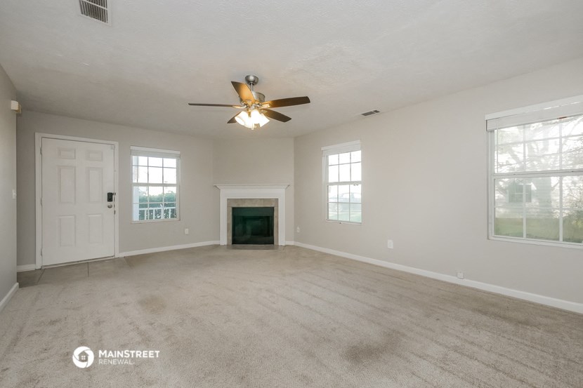the living room of an empty house with a ceiling fan