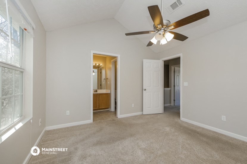the spacious living room with ceiling fan and carpeting