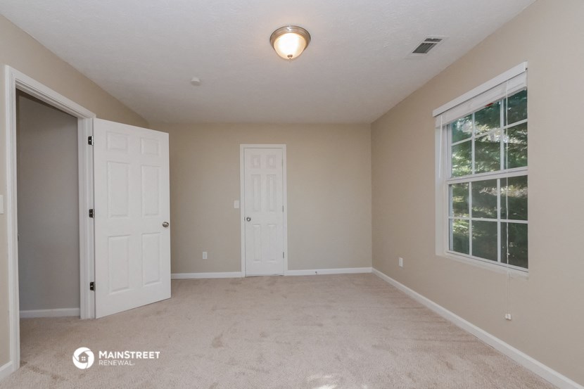 the spacious living room with two doors to the closet and a window