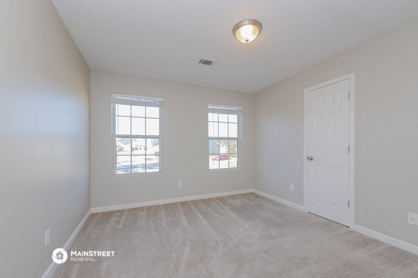 the spacious living room with white walls and a white door