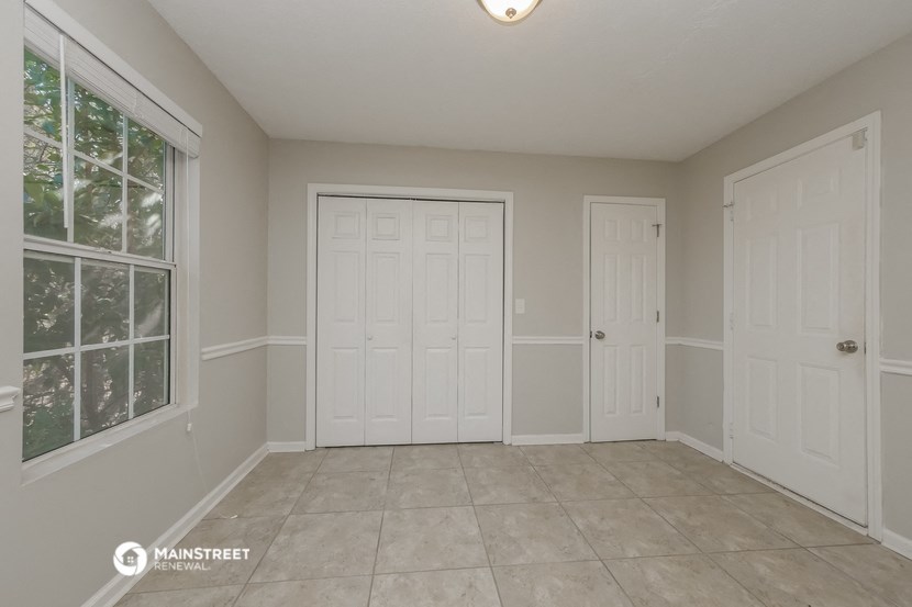 the living room of a home with two doors and a tiled floor