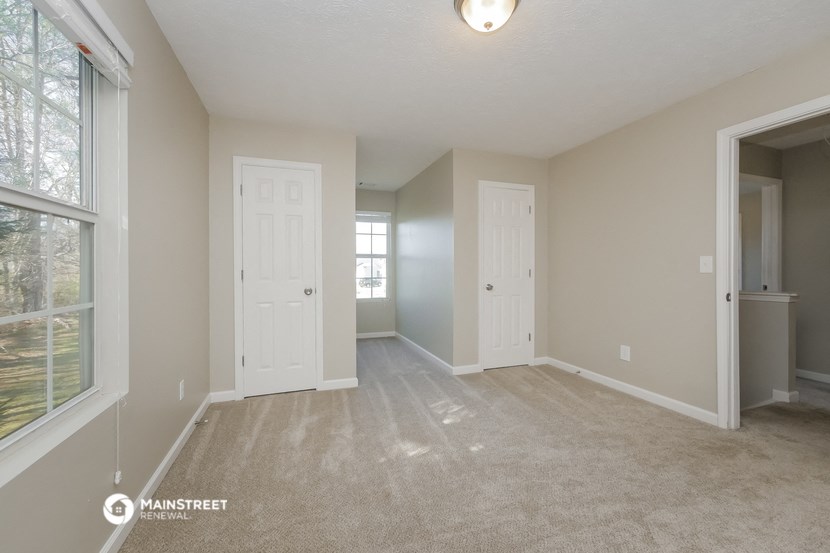 an empty living room with two doors and a window
