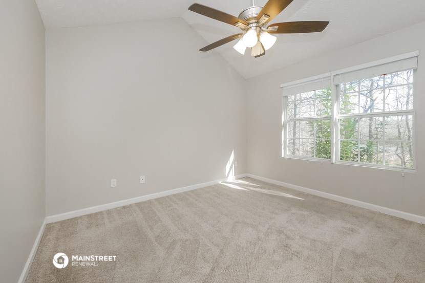 the spacious living room with carpet and a ceiling fan