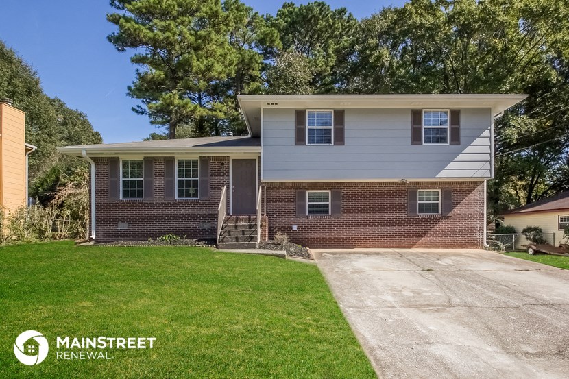 a small brick house with white siding and green grass