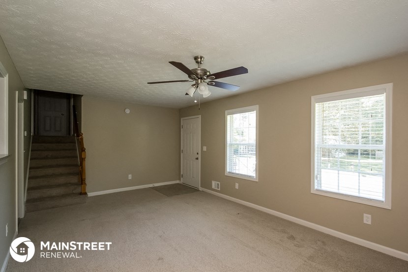 the living room of an empty house with a ceiling fan