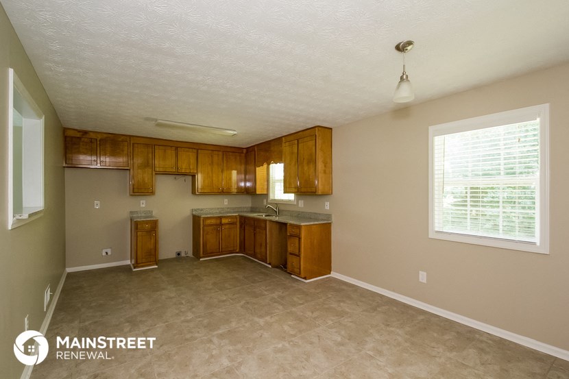 an empty kitchen with wooden cabinets and a window