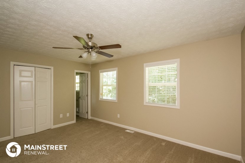 a living room with a ceiling fan and a white door