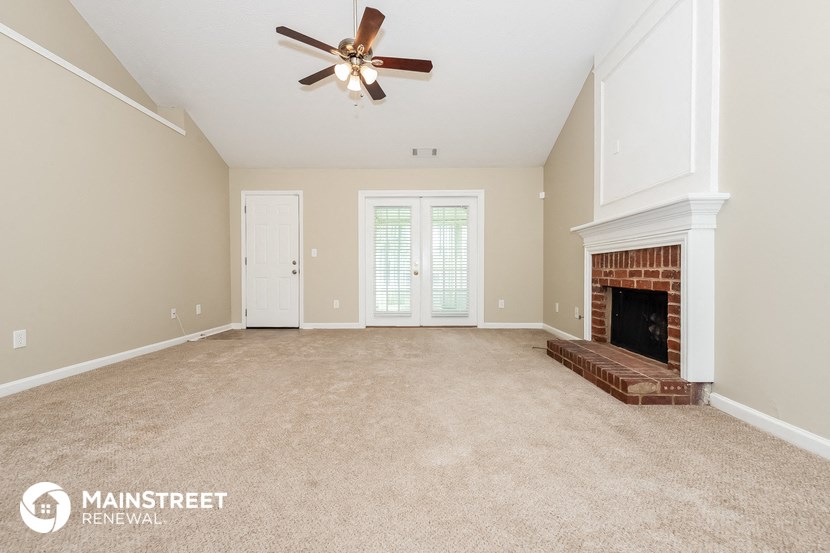an empty living room with a fireplace and a ceiling fan