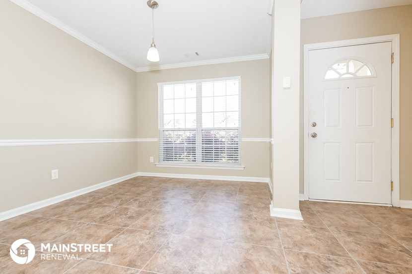 an empty living room with a white door and a window