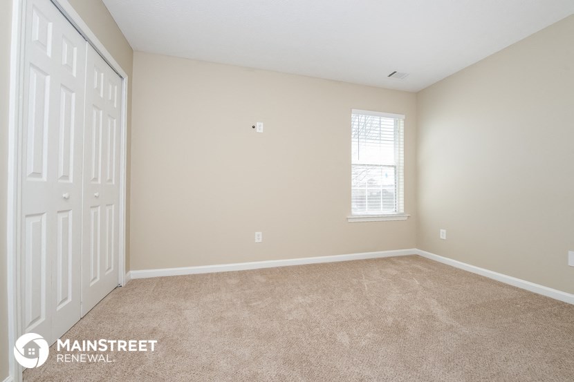 a bedroom with carpet and a window and a white door