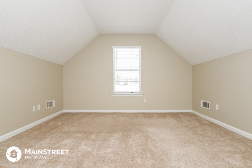 the upstairs loft of a home with carpet and a window
