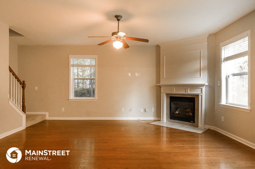 an empty living room with a fireplace and a ceiling fan