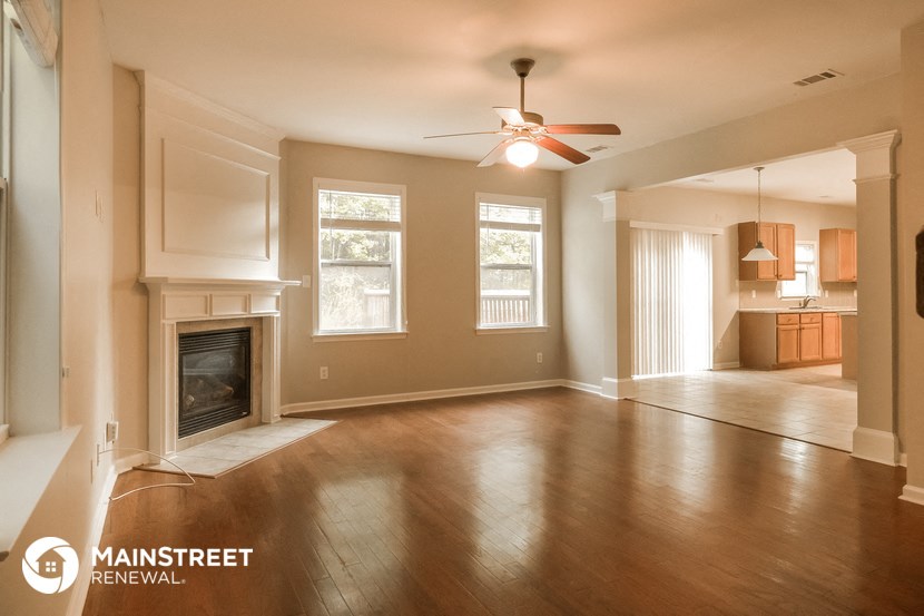 an empty living room with a fireplace and a ceiling fan