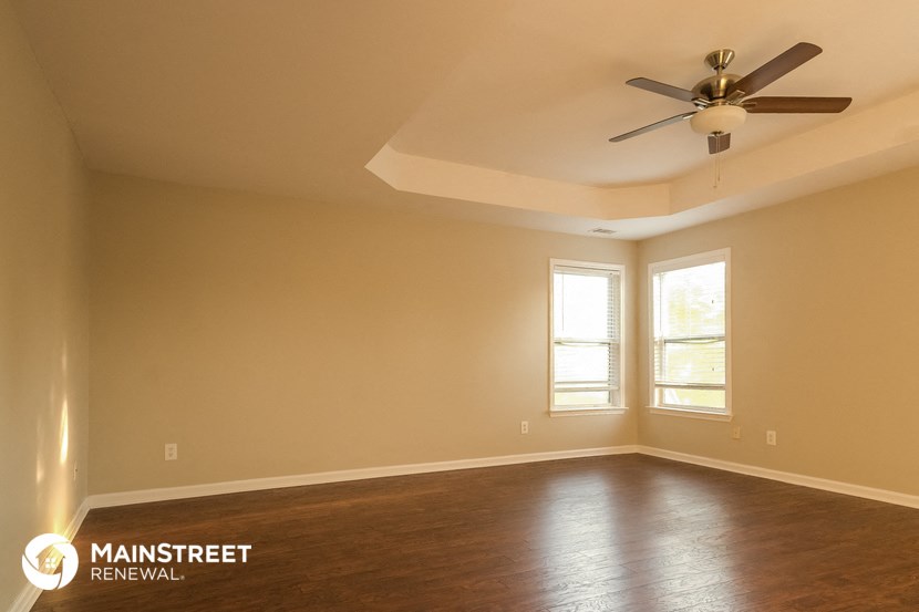 the living room of an empty house with a ceiling fan
