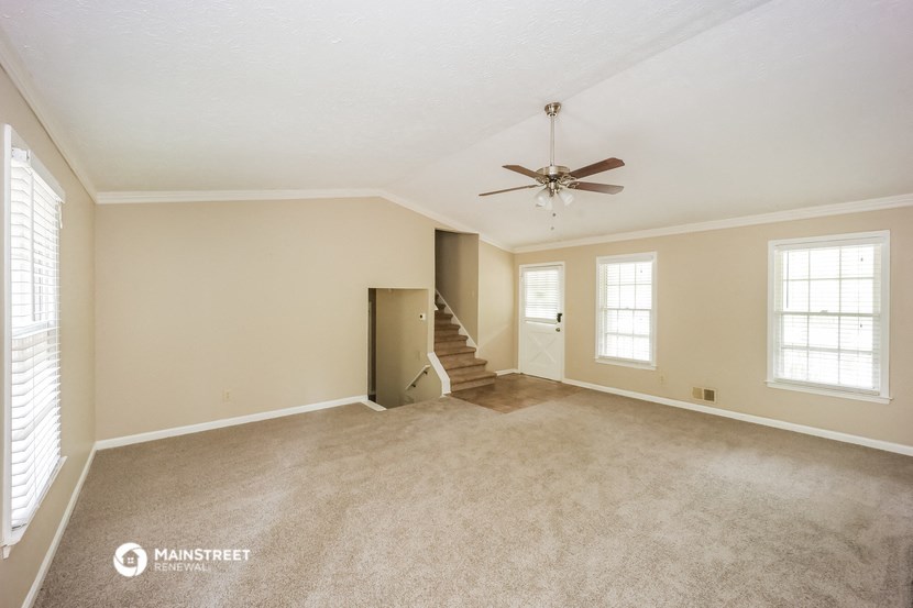 an empty living room with carpet and a ceiling fan
