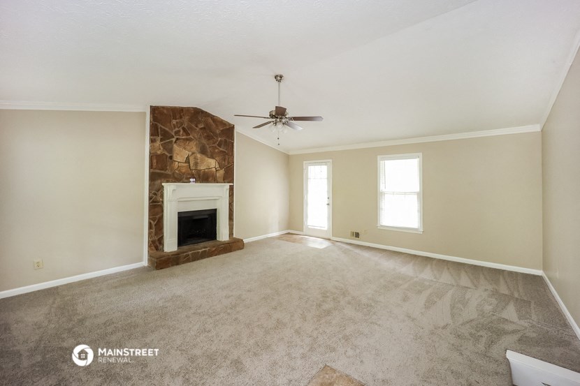 an empty living room with a fireplace and a ceiling fan