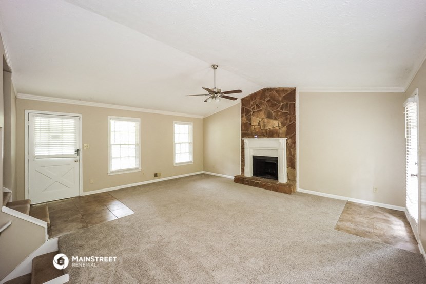 an empty living room with a fireplace and a ceiling fan