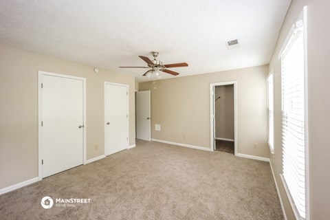 a spacious living room with carpet and a ceiling fan
