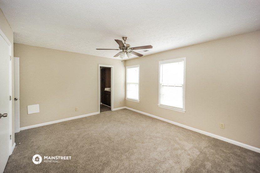 the spacious living room with carpet and ceiling fan