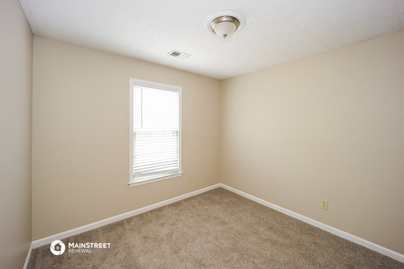 an empty room with a window and carpet