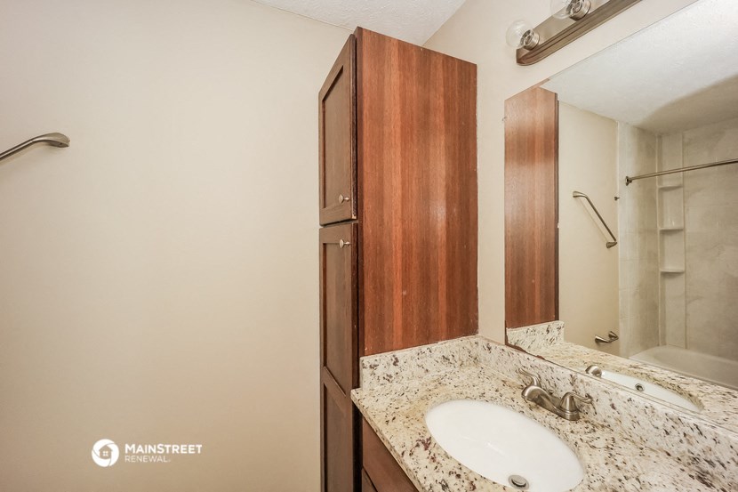 a bathroom with a sink and a shower and a wooden cabinet