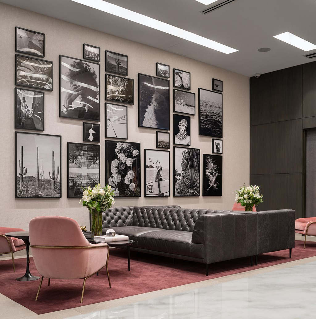 A living room with a grey couch, pink armchair, and a coffee table with a vase of flowers on it.
