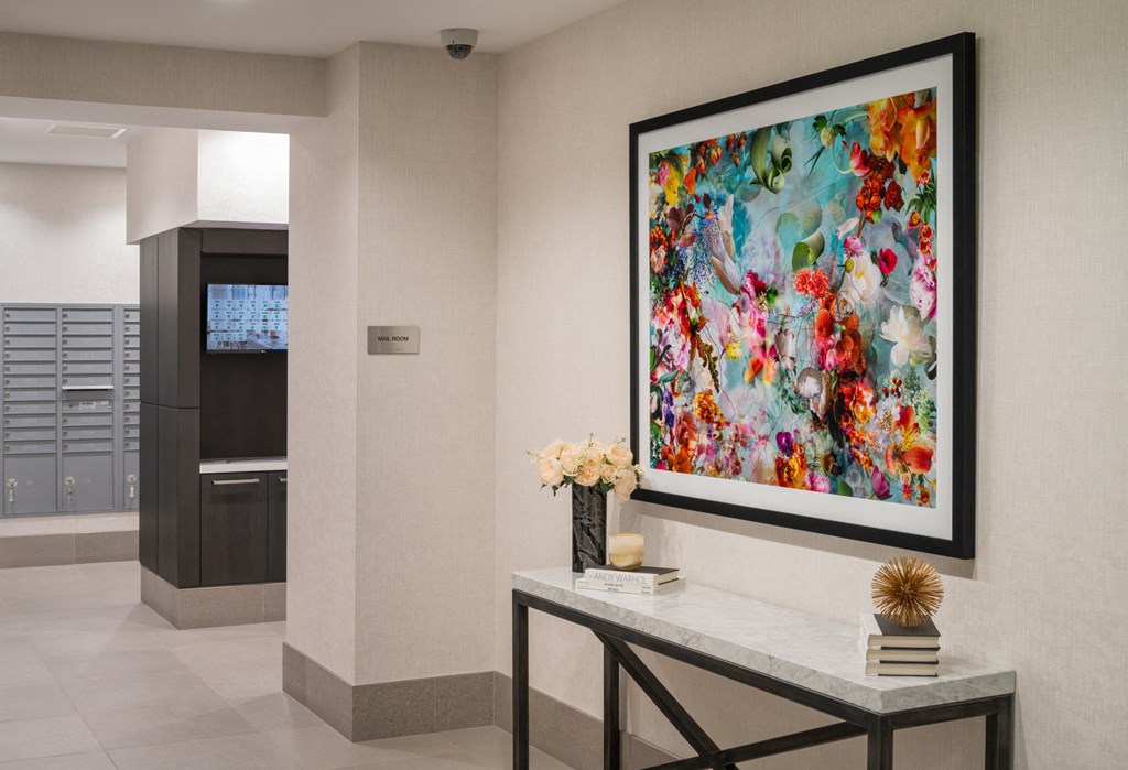 A framed artwork with a floral pattern hangs on a wall above a console table.