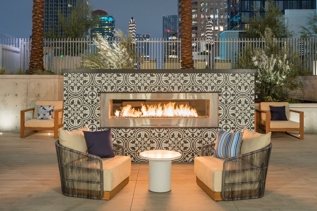 A patio with a fireplace and chairs.