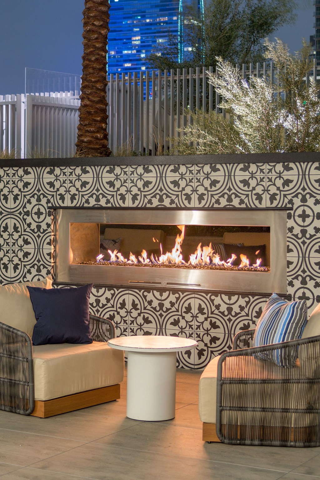 A fireplace with a black and white tile surround is lit with a fire in it.