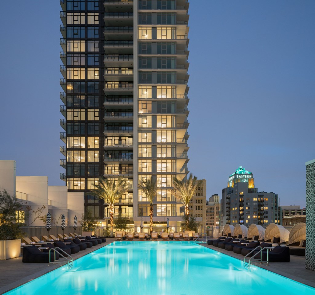 A large swimming pool in front of a tall building at dusk.