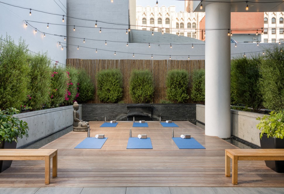 A yoga class is taking place on a wooden deck with blue mats.