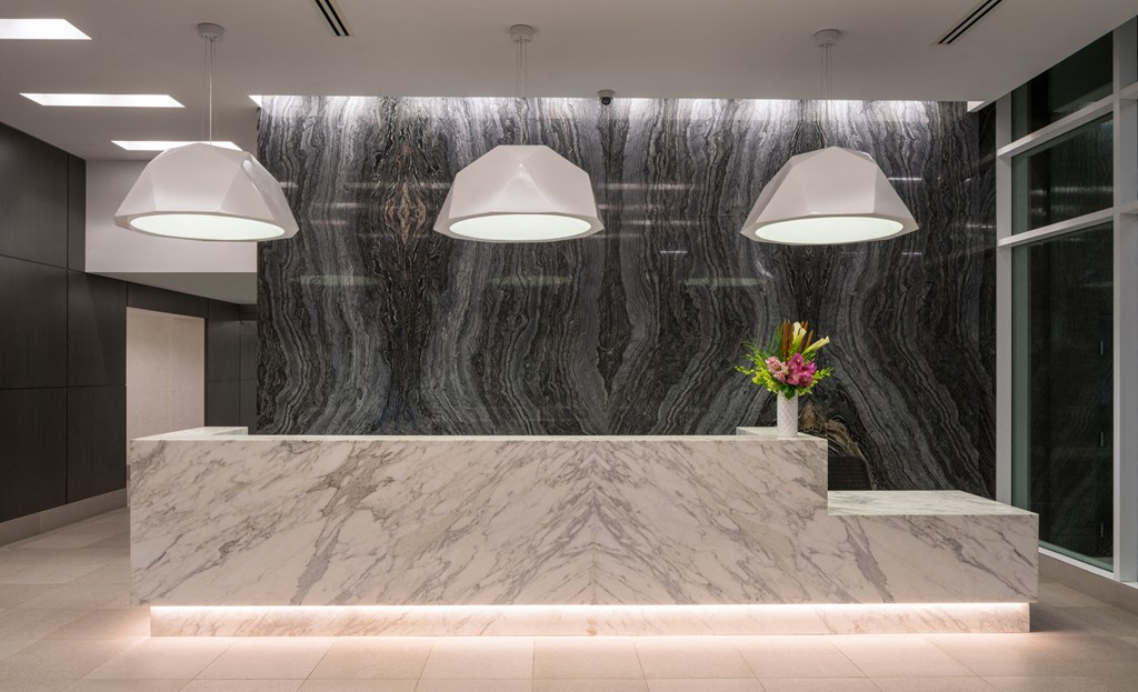 A reception area with a marble counter and three hanging lights.
