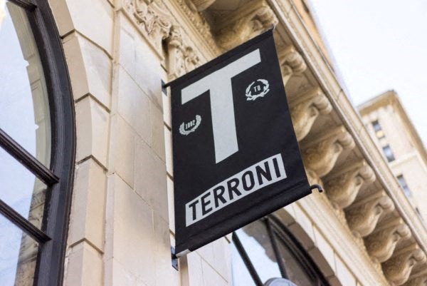 A black sign with a white letter T and the word Terroni below it hangs on a building.