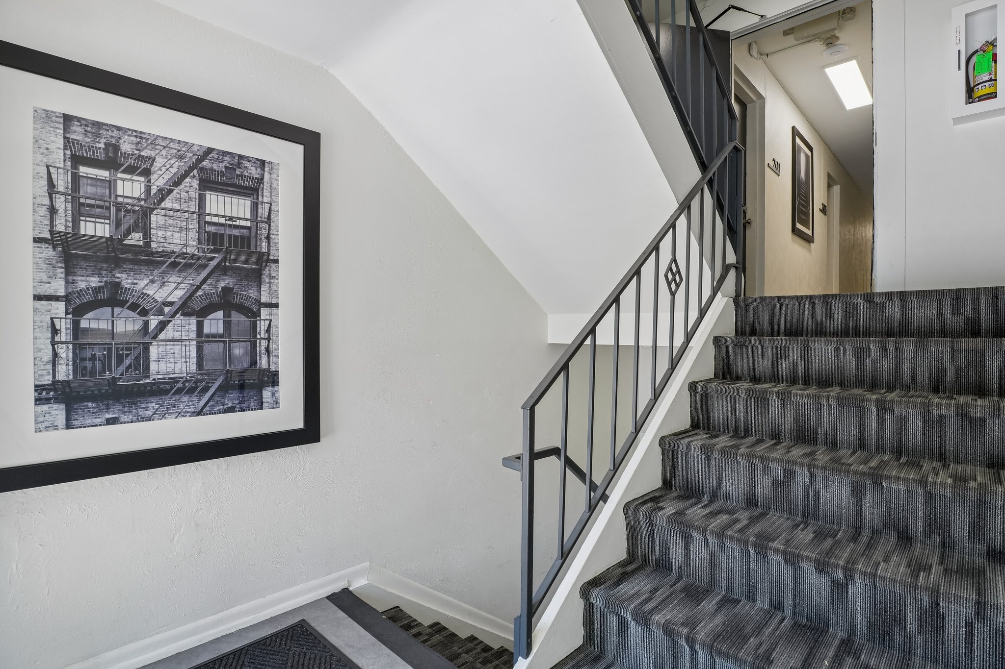 A staircase with a black railing and a picture of a building on the wall.
