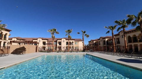 a swimming pool with palm trees in front of some apartments
