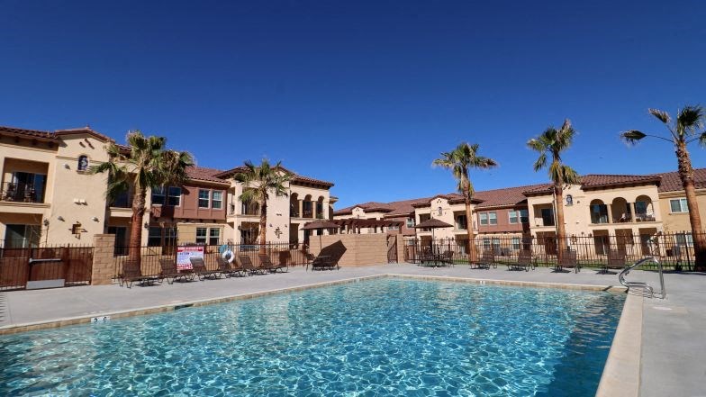 a swimming pool with palm trees in front of some apartments