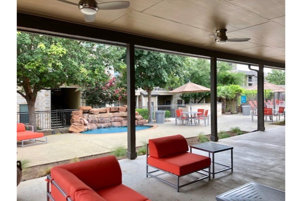 a patio with red chairs and a swimming pool