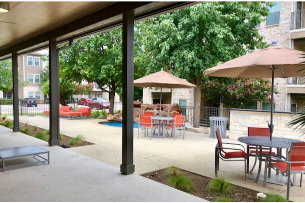 a patio with tables and chairs and a pool in front of a building