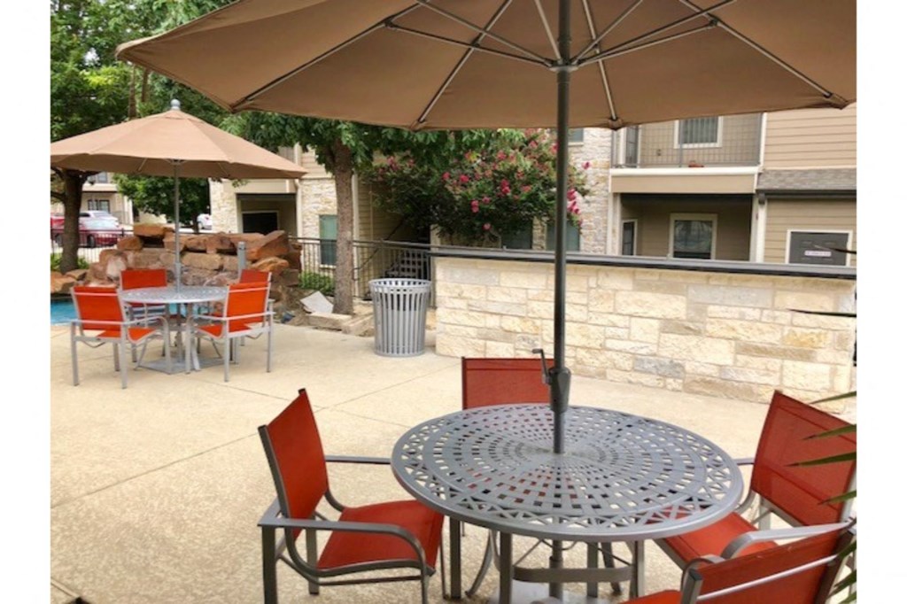 a patio with tables and chairs and an umbrella