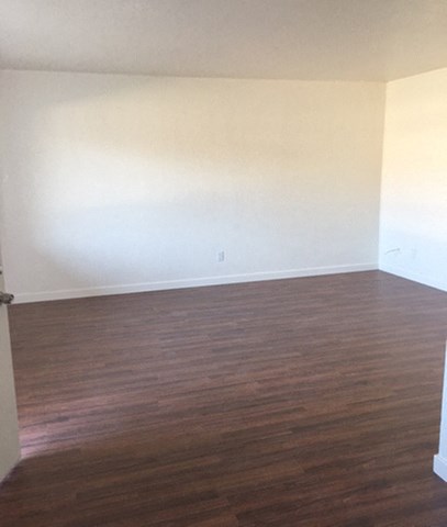an empty living room with wood floors and white walls