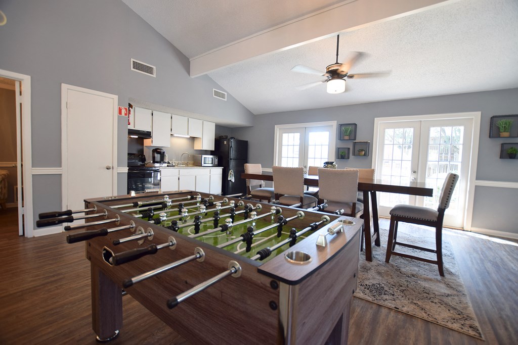 an open living room with a foosball table and a dining table with chairs