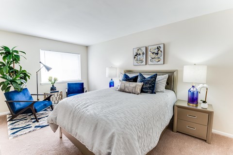 A bedroom with a large bed and a blue chair.